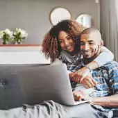 couple smiling looking at laptop