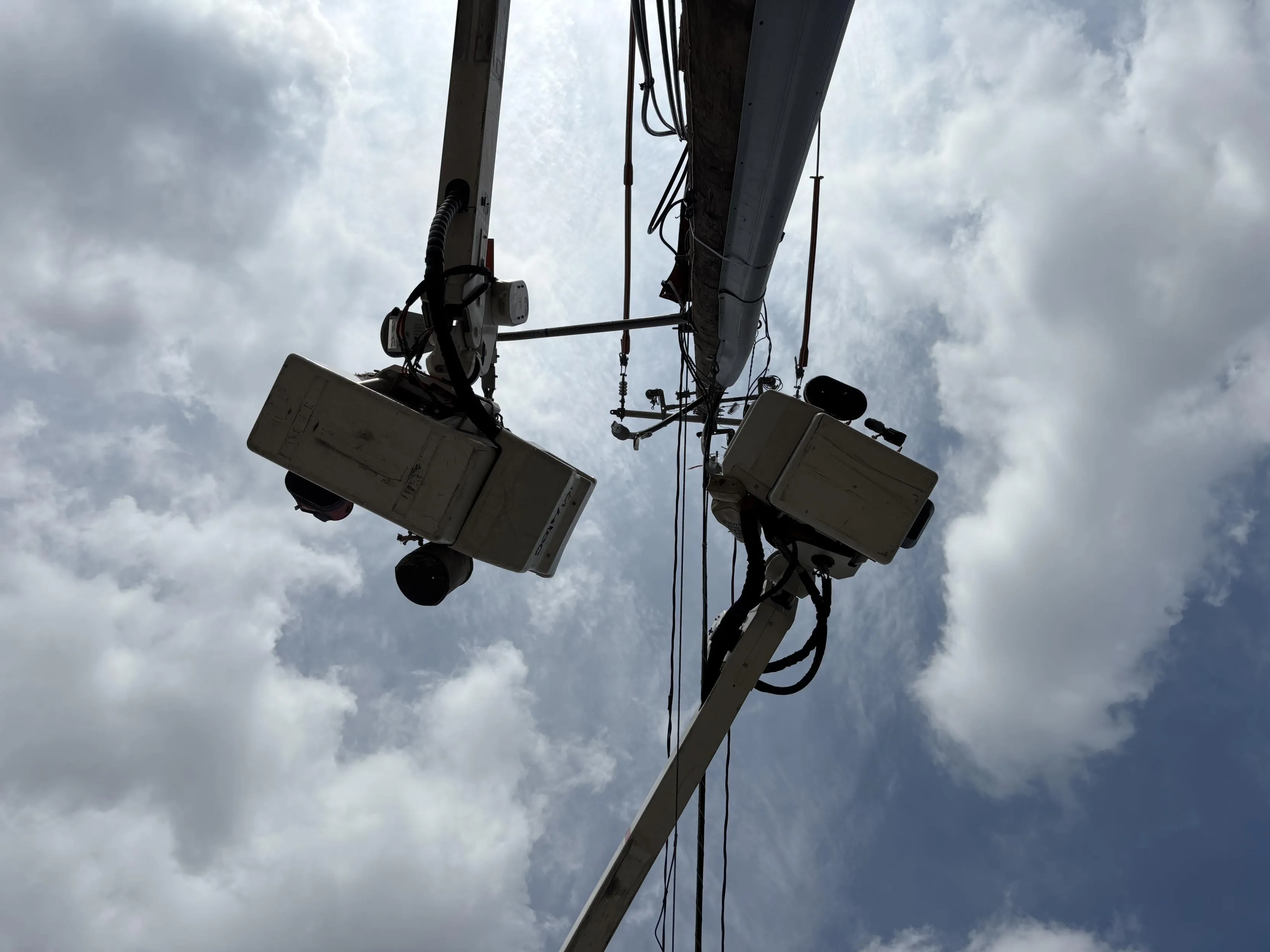 Two surveillance cameras mounted on a pole against a cloudy sky background.